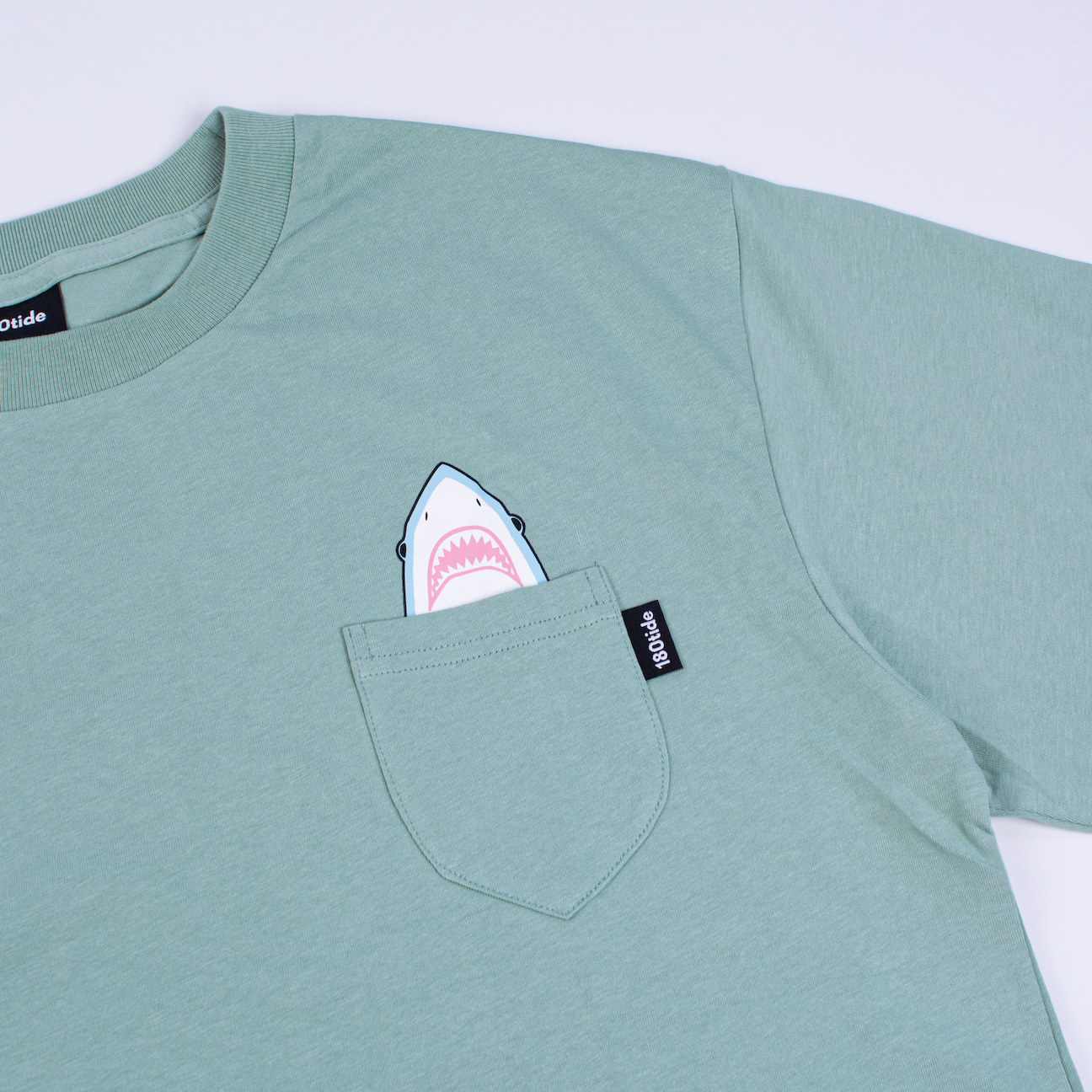 Shark wearing rubber ducky floatie sage green pocket tee. 