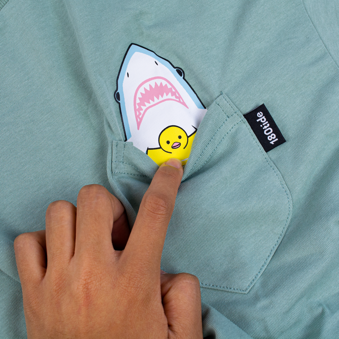 Shark wearing rubber ducky floatie sage green pocket tee. 