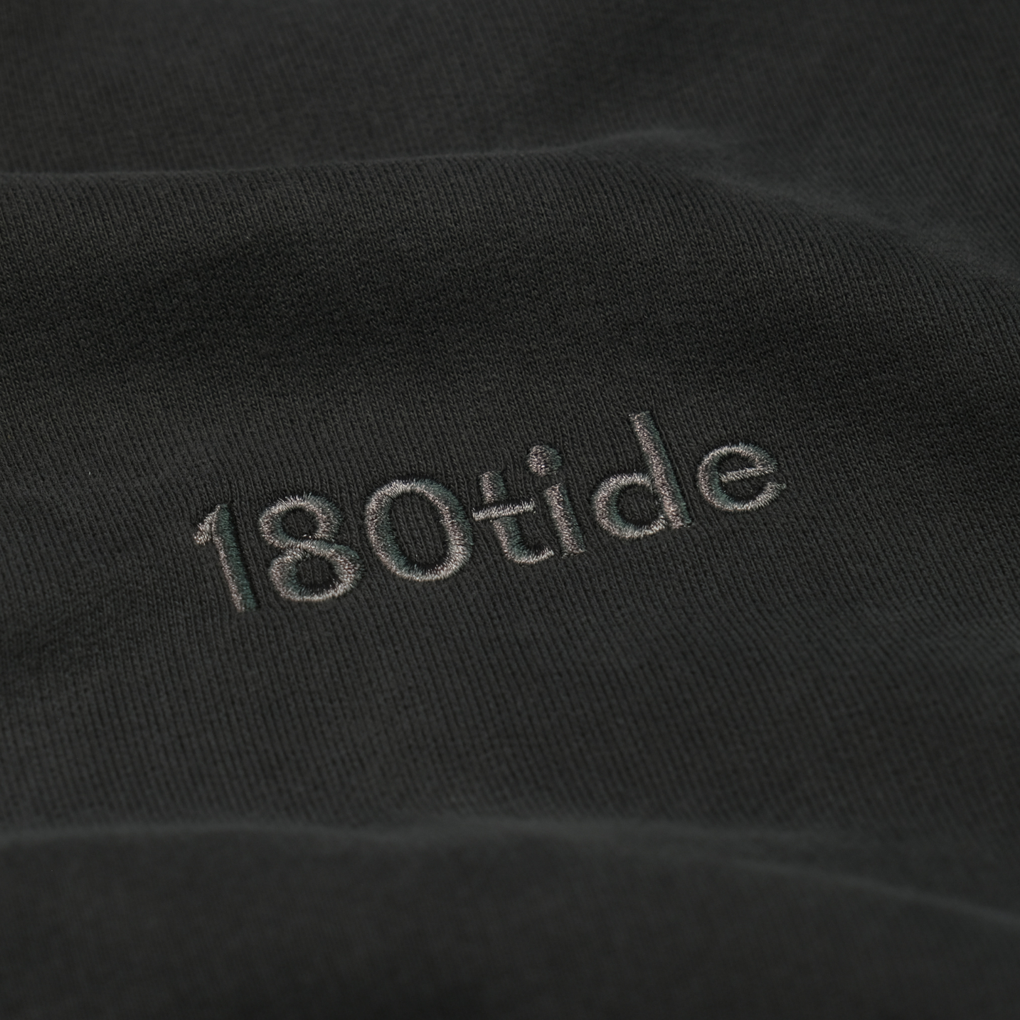 Close-up of the tonal 180tide chest embroidery on the Onyx Logo Hoodie