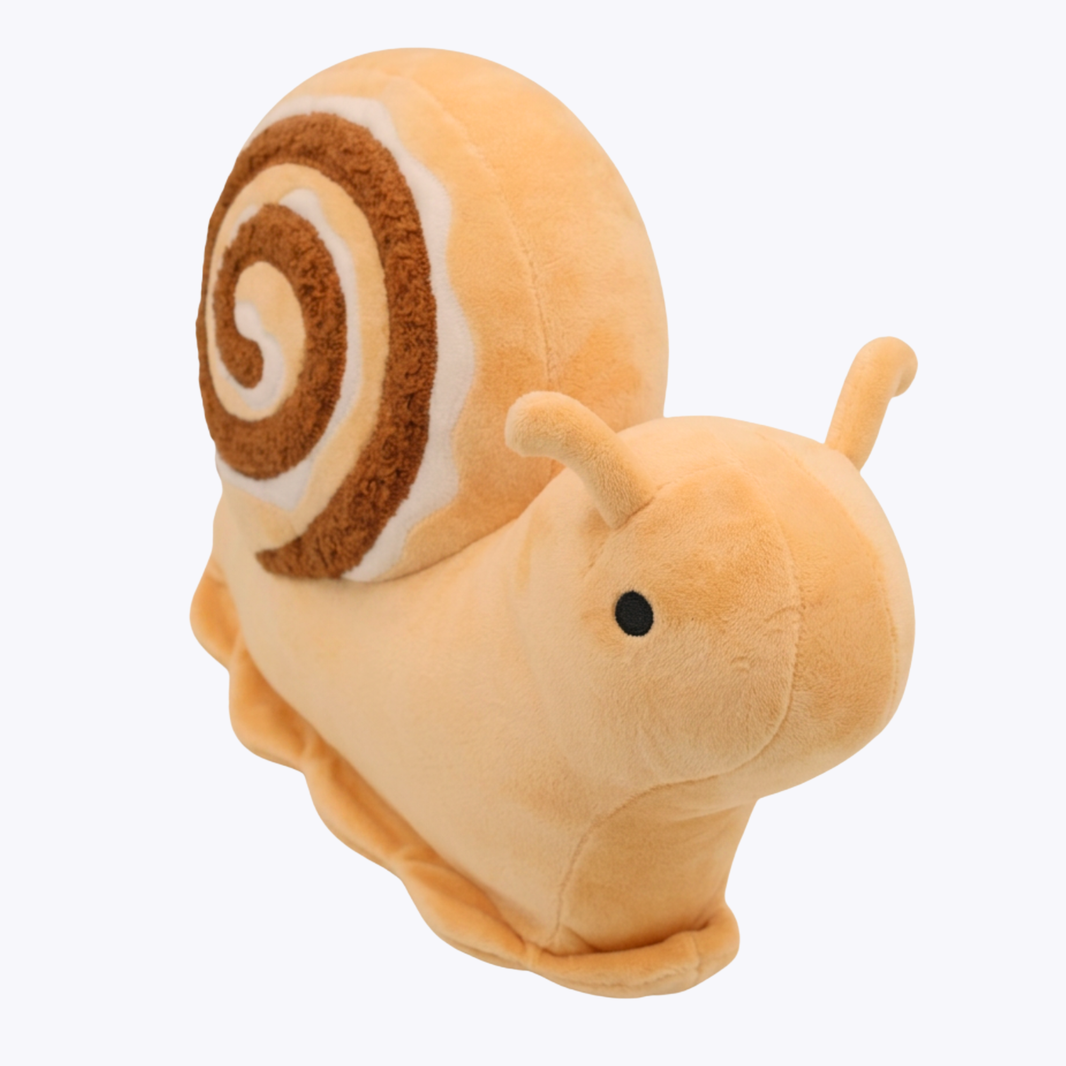 A plush snail toy with a soft peach-colored body and a spiral shell in brown, cream, and peach, shown on a plain white background.