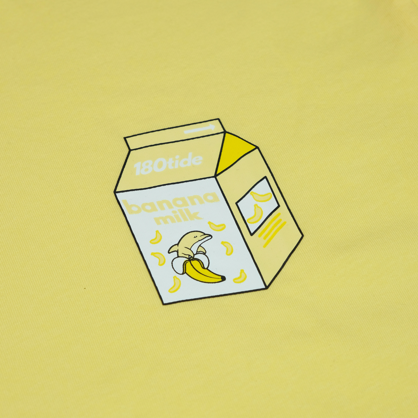 Close-up of Bandan the Banana Dolphin in the banana milk carton chest print on the Bandan Banana Dolphin Milk Tee