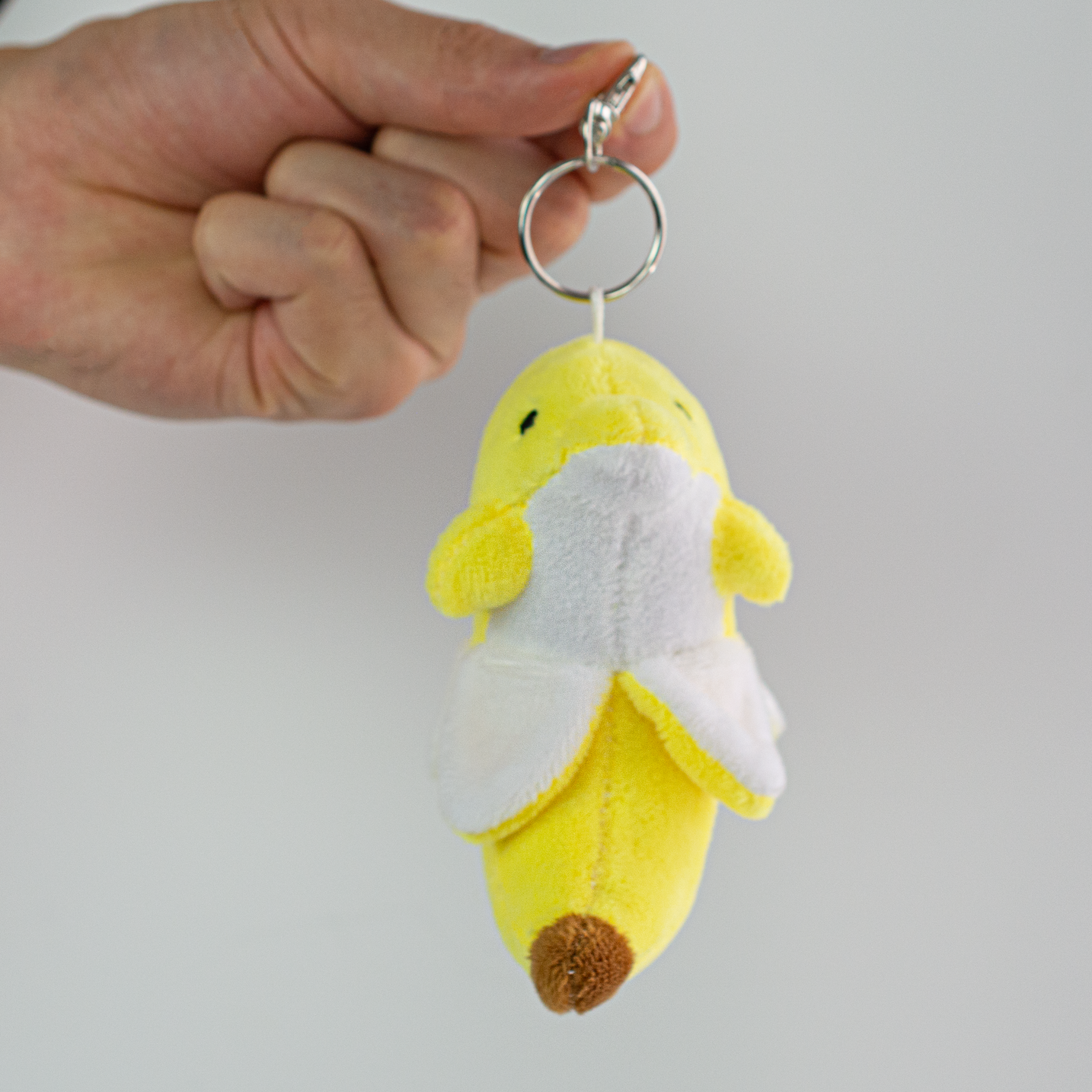 Bandan the Banana Dolphin Plush Keychain, dangling from hand side view