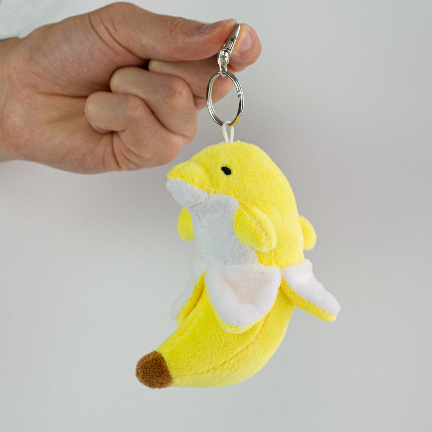 Bandan the Banana Dolphin Plush Keychain, dangling from hand