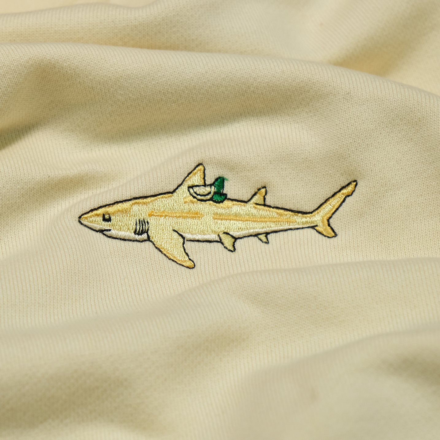 Close-up of the Pucker the Lemon Shark chest embroidery on the Lemon Yellow hoodie