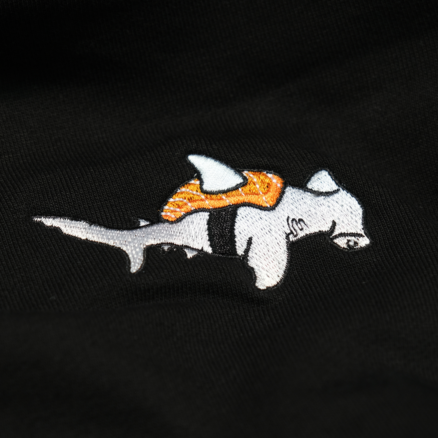 Close-up of the Takashi the Sushi Hammerhead chest embroidery on the Onyx hoodie