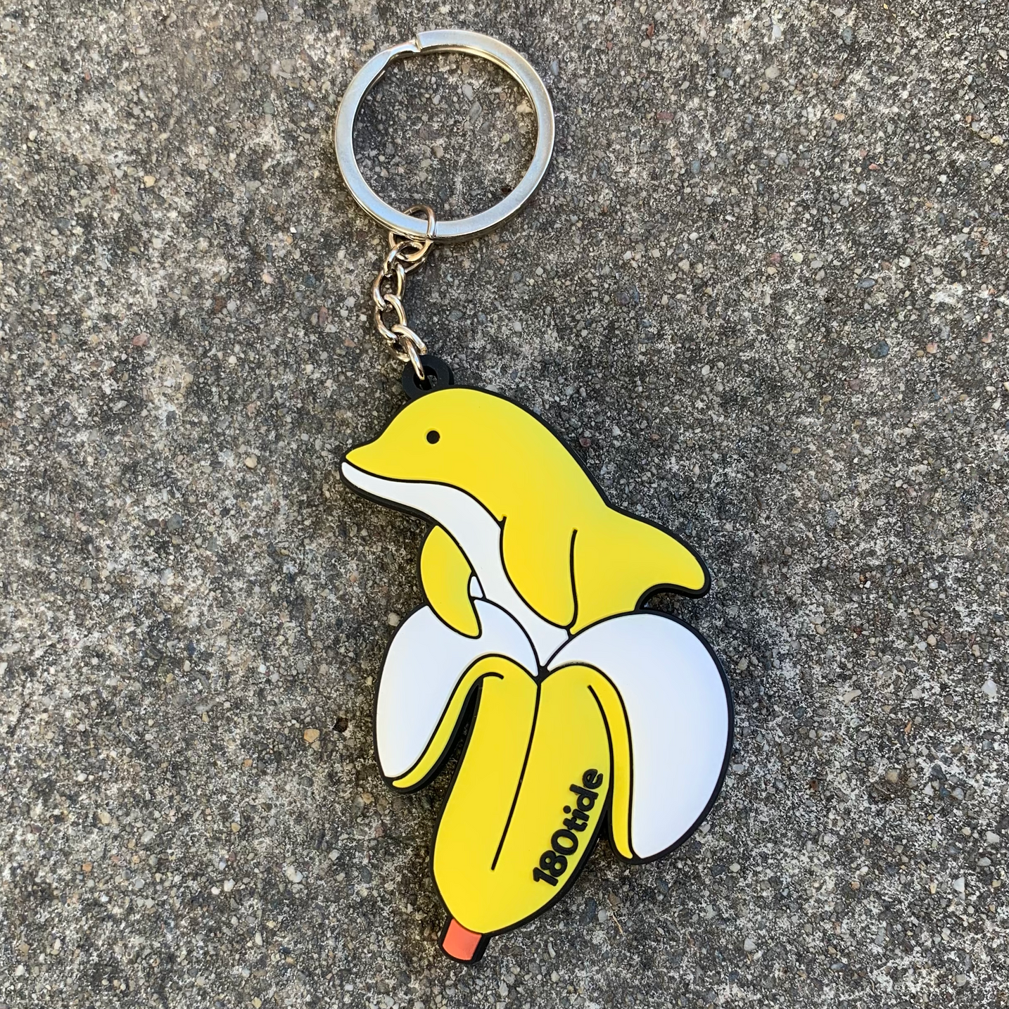 Bandan the Banana Dolphin Rubber Keychain, lifestyle on pavement